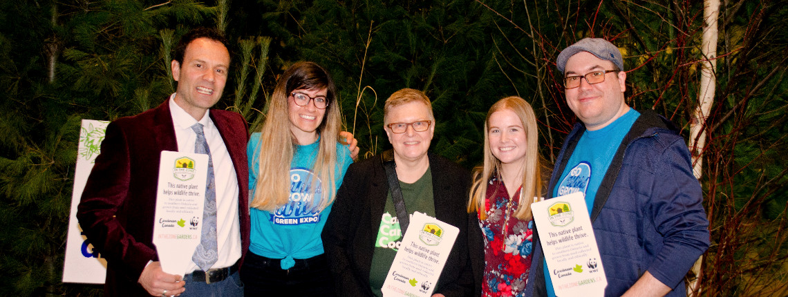Photo of Carolinian Canada staff holding native plant tags in front of trees